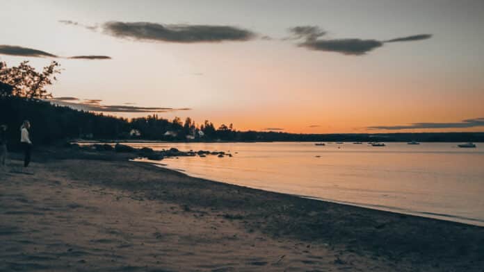 Solnedgång vid sandstrand.